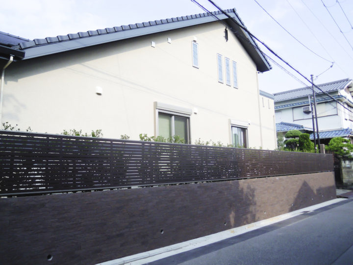 道路面からの プライバシー を守るため、横柄の 木調フェンスに 重厚感あるタイル貼りの塀。