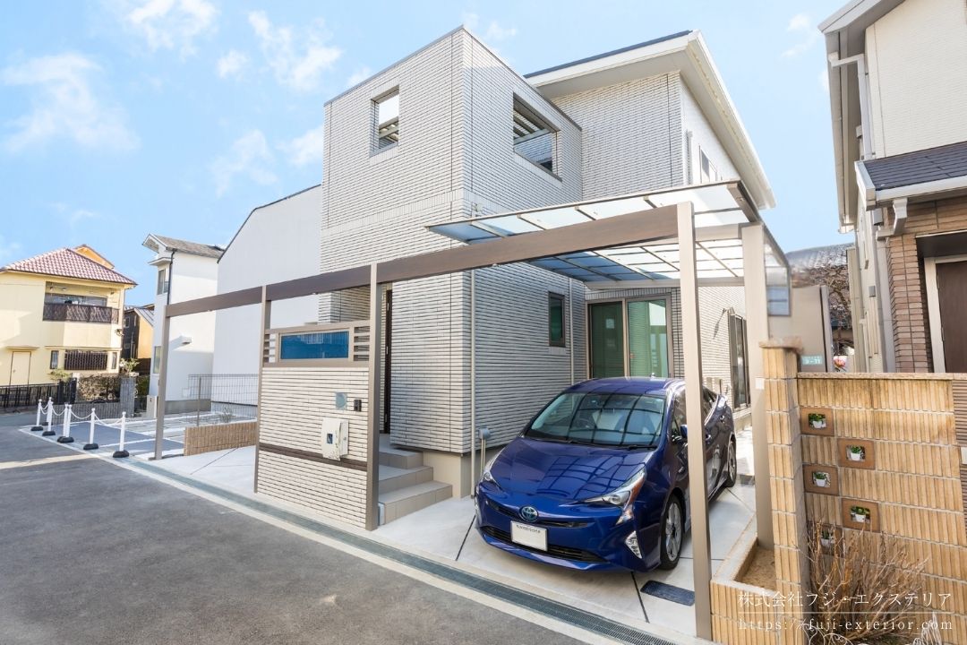 北摂地区の人気住宅地に完成した新築外構の施工事例。道路に面した玄関ドアの目隠しとして、建物と同じタイルを使用した門柱を設置し、左右のカースペースと一体化したアーチデザインで、建物と調和したファサードを実現。