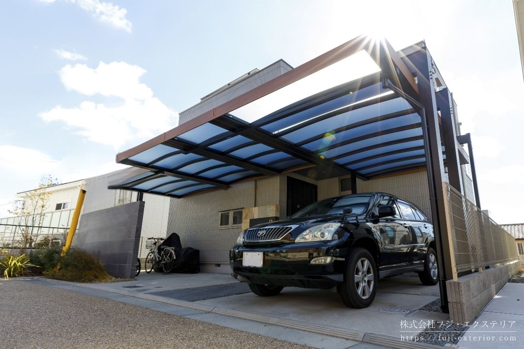 住宅の形状に合わせて屋根サイズを調整した三協アルミ「U.スタイル アゼスト」のカーポート施工事例。雨水排水のための水勾配を破風で隠す構造により、外観は一直線の水平デザインを実現。建築の基本である水平・垂直構成を活かし、機能性とデザイン性を高次元で両立した高級カーポート。