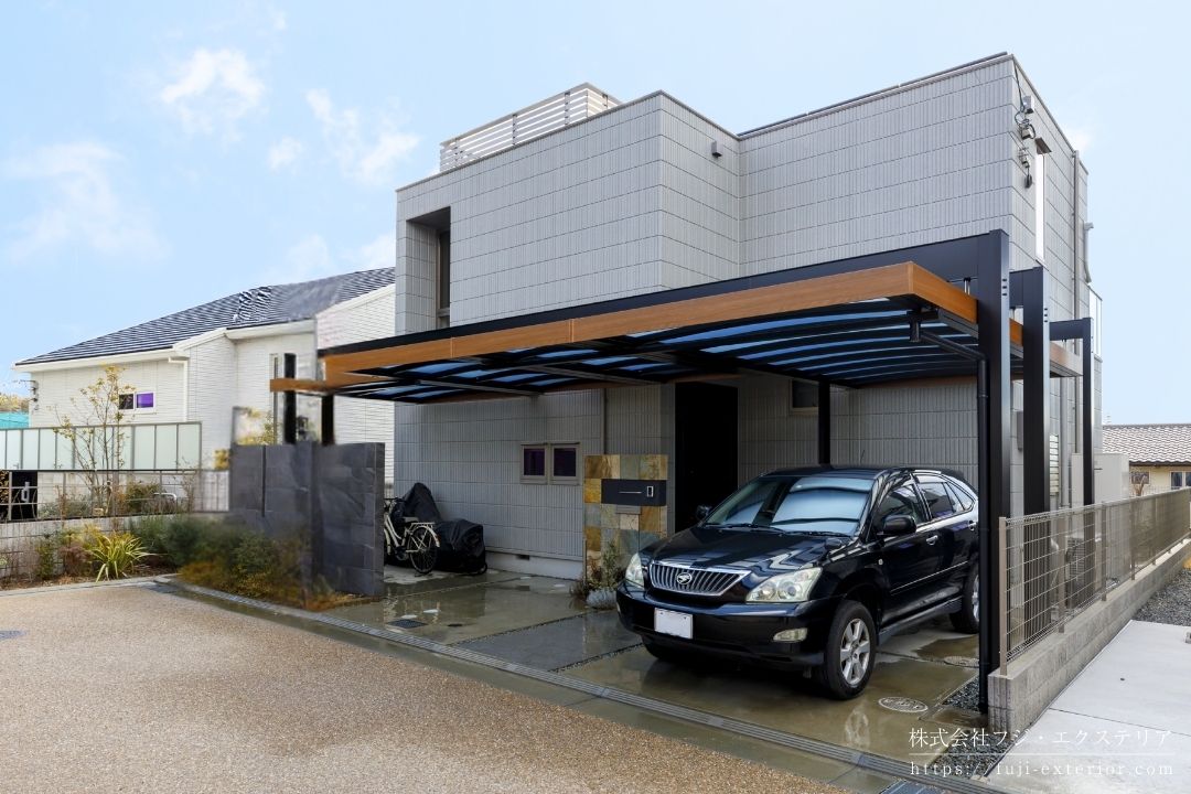 住宅の形状に合わせて屋根サイズを調整した三協アルミ「U.スタイル アゼスト」のカーポート施工事例。雨水排水のための水勾配を破風で隠す構造により、外観は一直線の水平デザインを実現。建築の基本である水平・垂直構成を活かし、機能性とデザイン性を高次元で両立した高級カーポート。