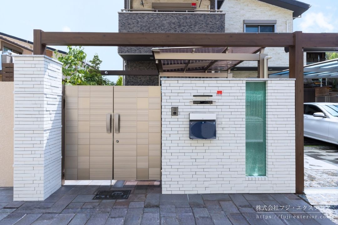 アクセントでガラスを埋め込んだタイル張りの白い門柱。梁でシャッターゲートと繋いでいます。