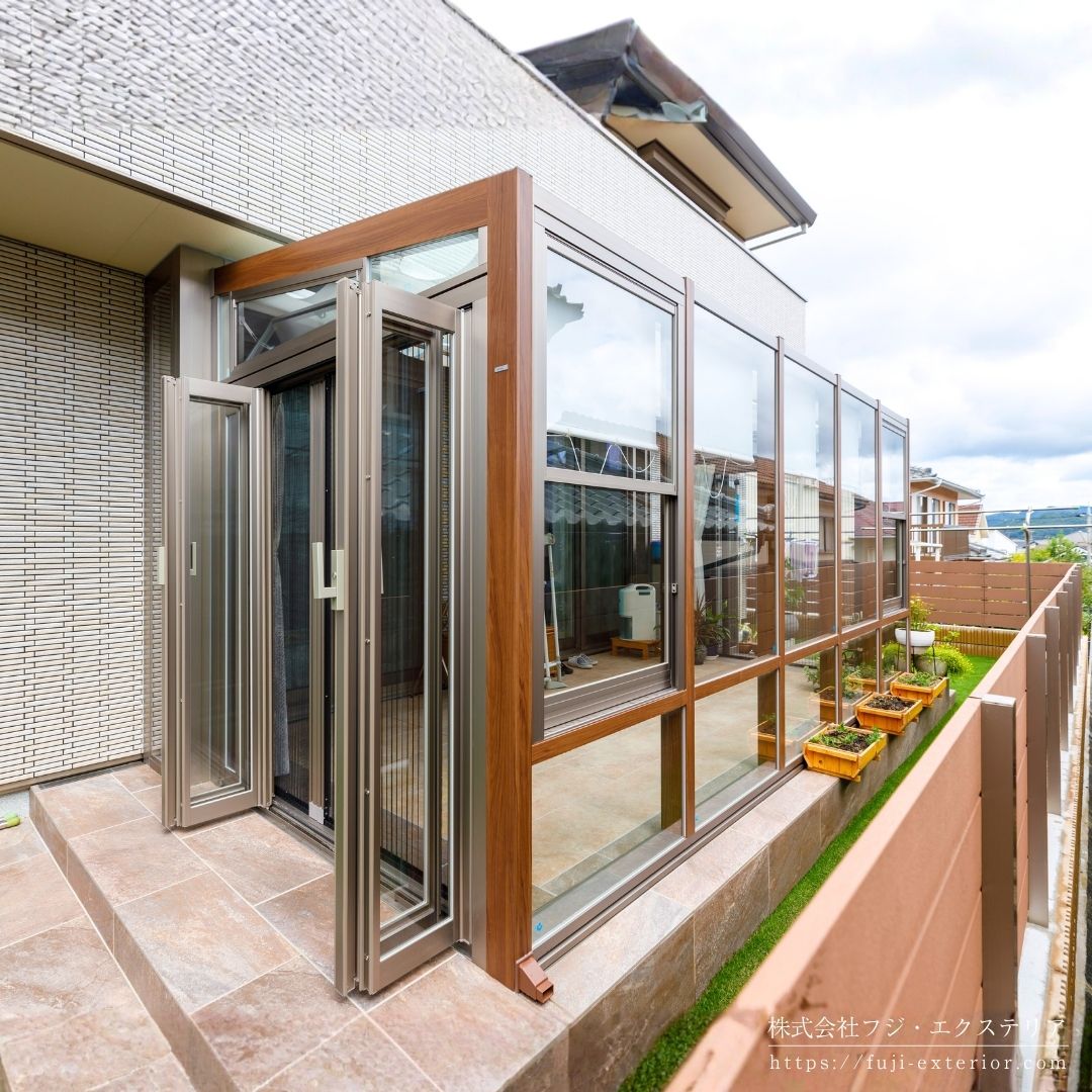 ガーデンルーム LIXIL ココマⅡ。左右側面は折れ戸仕様で前面は強化FIXガラス。換気用の上げ下げ窓、側面喚気窓、内部日除け、ロールカーテン、LEDスクエアライト、可動竿掛け付きのフル装備バージョンです。