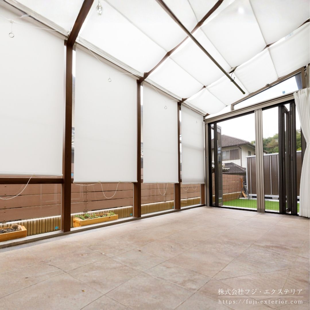 ガーデンルーム LIXIL ココマⅡ。左右側面は折れ戸仕様で前面は強化FIXガラス。換気用の上げ下げ窓、側面喚気窓、内部日除け、ロールカーテン、LEDスクエアライト、可動竿掛け付きのフル装備バージョンです。
