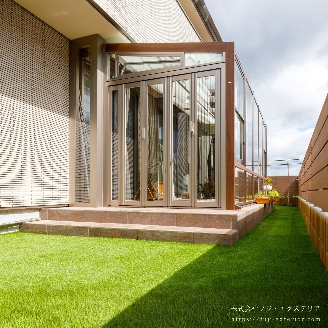 ガーデンルーム LIXIL ココマⅡ。左右側面は折れ戸仕様で前面は強化FIXガラス。換気用の上げ下げ窓、側面喚気窓、内部日除け、ロールカーテン、LEDスクエアライト、可動竿掛け付きのフル装備バージョンです。