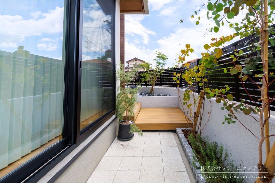 犬走りの床材は遮熱性能のあるコンクリート平板 ダルメペイブ 。ナチュラルなグレーに白と黒の石を自然な形で散りばめており、リラックスした雰囲気を作り出します。花壇側面には排水用溝も造り、水たまりが出来にくい工夫がされています。