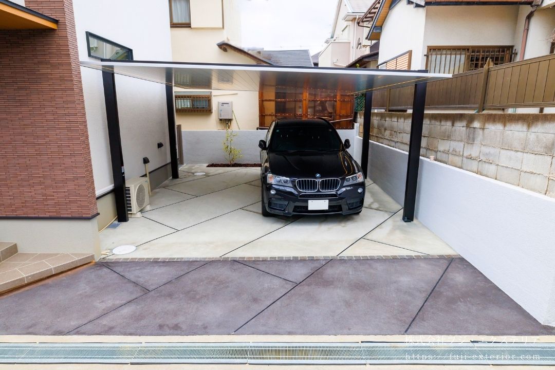 カーポートは LIXIL カーポートSC。シャープですっきりしたフラットデザインが魅力です。道路側のアプローチはコンクリートに色を付けてガレージとの境界を造っています。