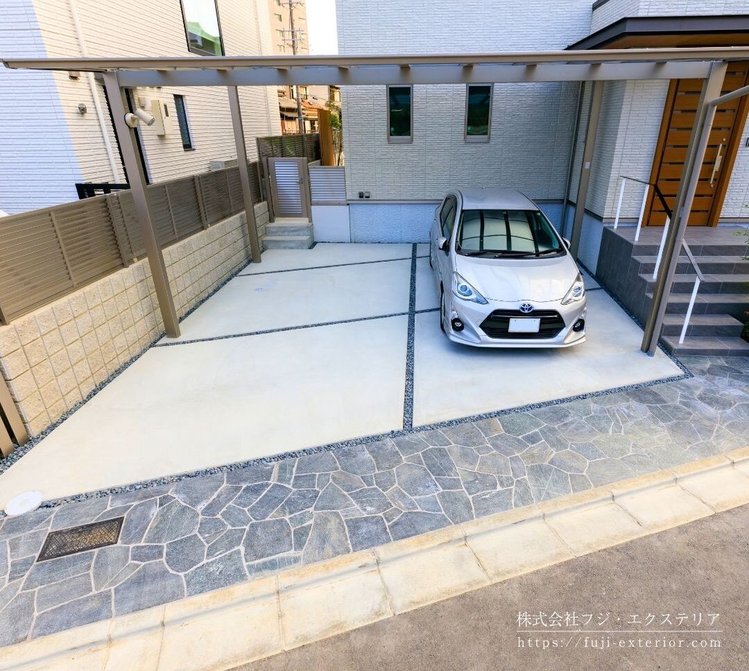 カーポートはLIXIL フーゴFワイド 2台用。屋根材の熱線ポリカーボネートは、光を採り込みながらも紫外線はほぼ100％カット。
台形型のガレージはブラック系乱形石を敷き。カーポートの排水は地中埋設したパイプで受け、年月が経っても水垢でコンクリートが変色しない様に工夫しました。