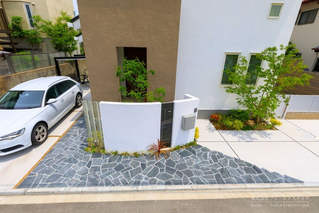 黒系タイルを敷いたアプローチ。植栽と調和したシンプルモダンデザイン。