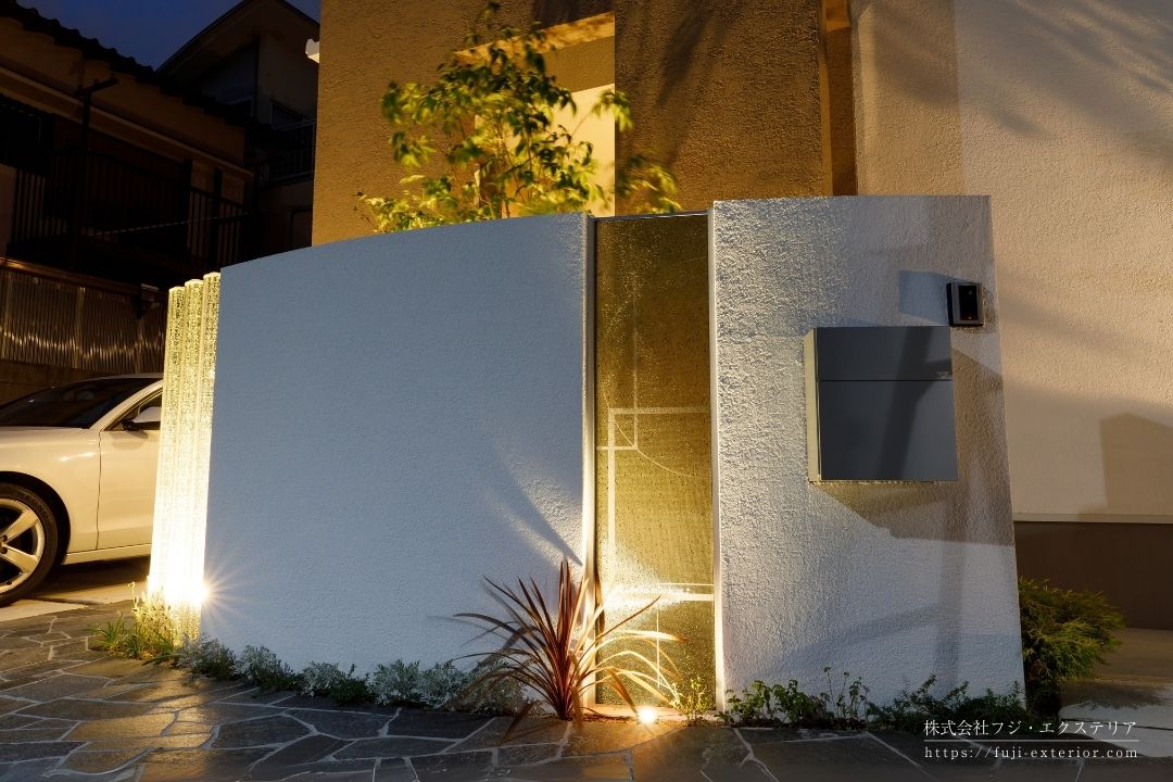 夜には表札のガラス ティンクルが美しく光ります。アオダモの足元にもスポットライトを入れ、明るく安全な門まわりを演出しています。