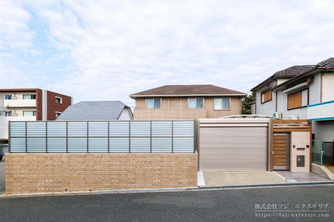 大阪の戸建て住宅における外構フルリノベーション施工例。LIXILプラスGのフレームゲートと電動オーバードアで構成された高級感のあるクローズ外構の全景写真。