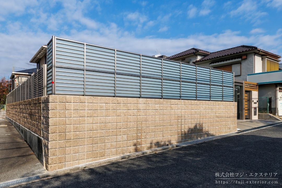 LIXILの採光ルーバーフェンス「サニーブリーズフェンスS型」の施工事例。目隠し機能を維持しつつ、特殊なブレード形状で光と風を通す、大阪の住宅リノベーションにおける境界フェンス設置。